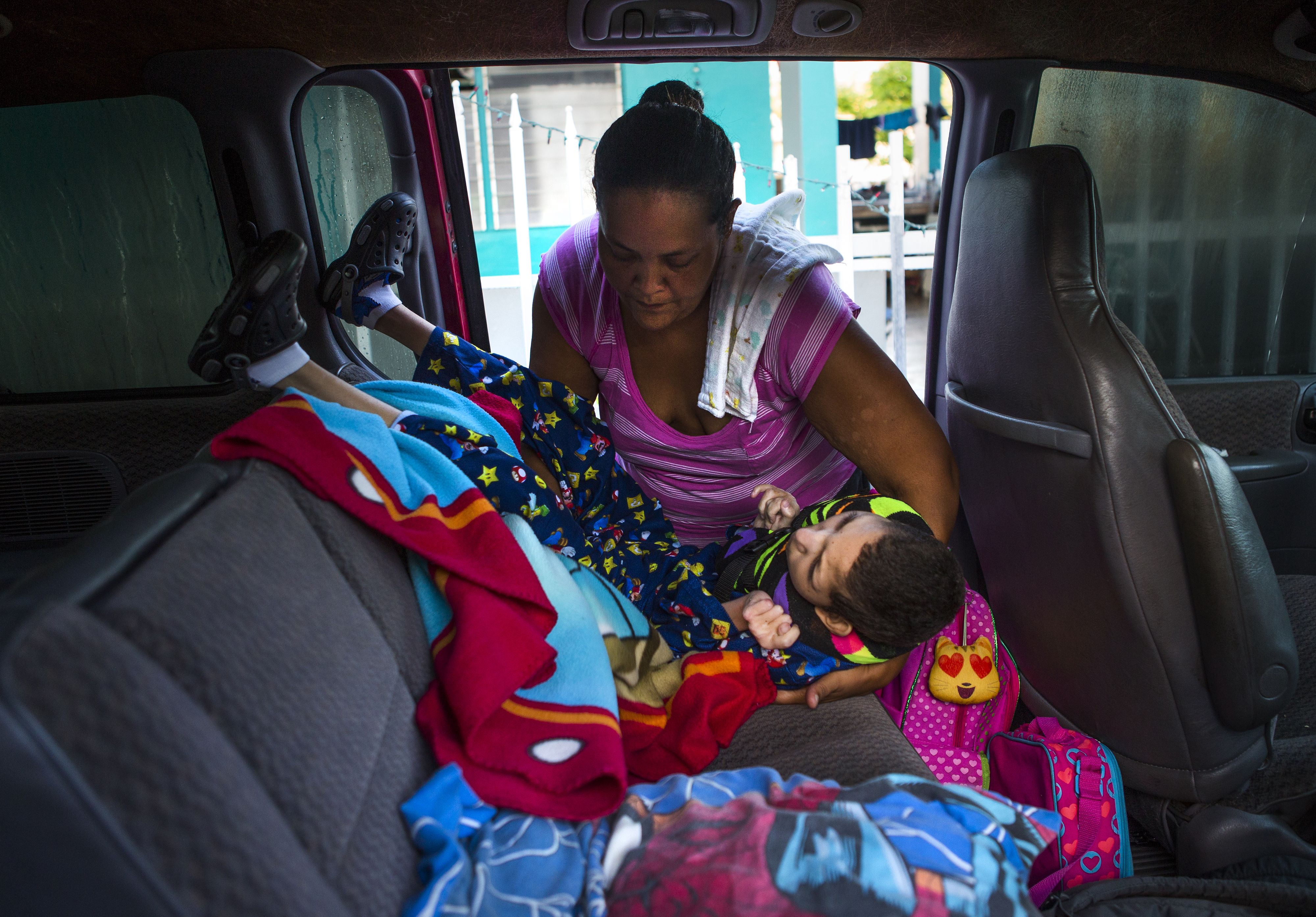 Karen Feliciano loads her son, Kenny, into the middle bench seat of her red Dodge Caravan to take him to school. Instead of driving him around the corner to a school built to accommodate his needs, she takes him to a building that is structurally prepared to withstand the strength of a Category 4 hurricane, but does not properly facilitate special education students like Kenny. Image by Ryan Michalesko. Puerto Rico, 2017.
