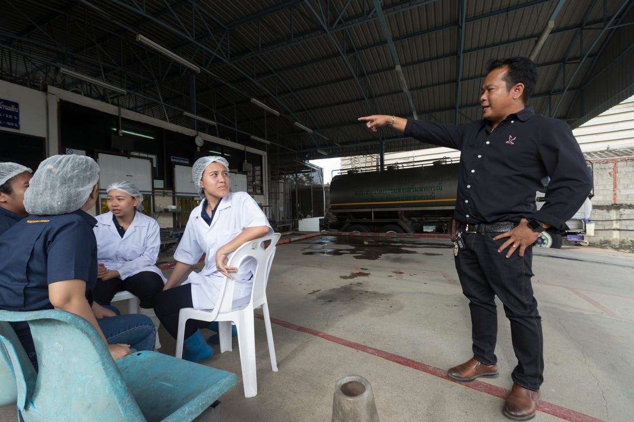 Manager Daiu Saingam talks with employees waiting for farmers to deliver milk at the Pakchong Dairy Cooperative in Pak Chong, Thailand. Image by Mark Hoffman. Thailand, 2019. 