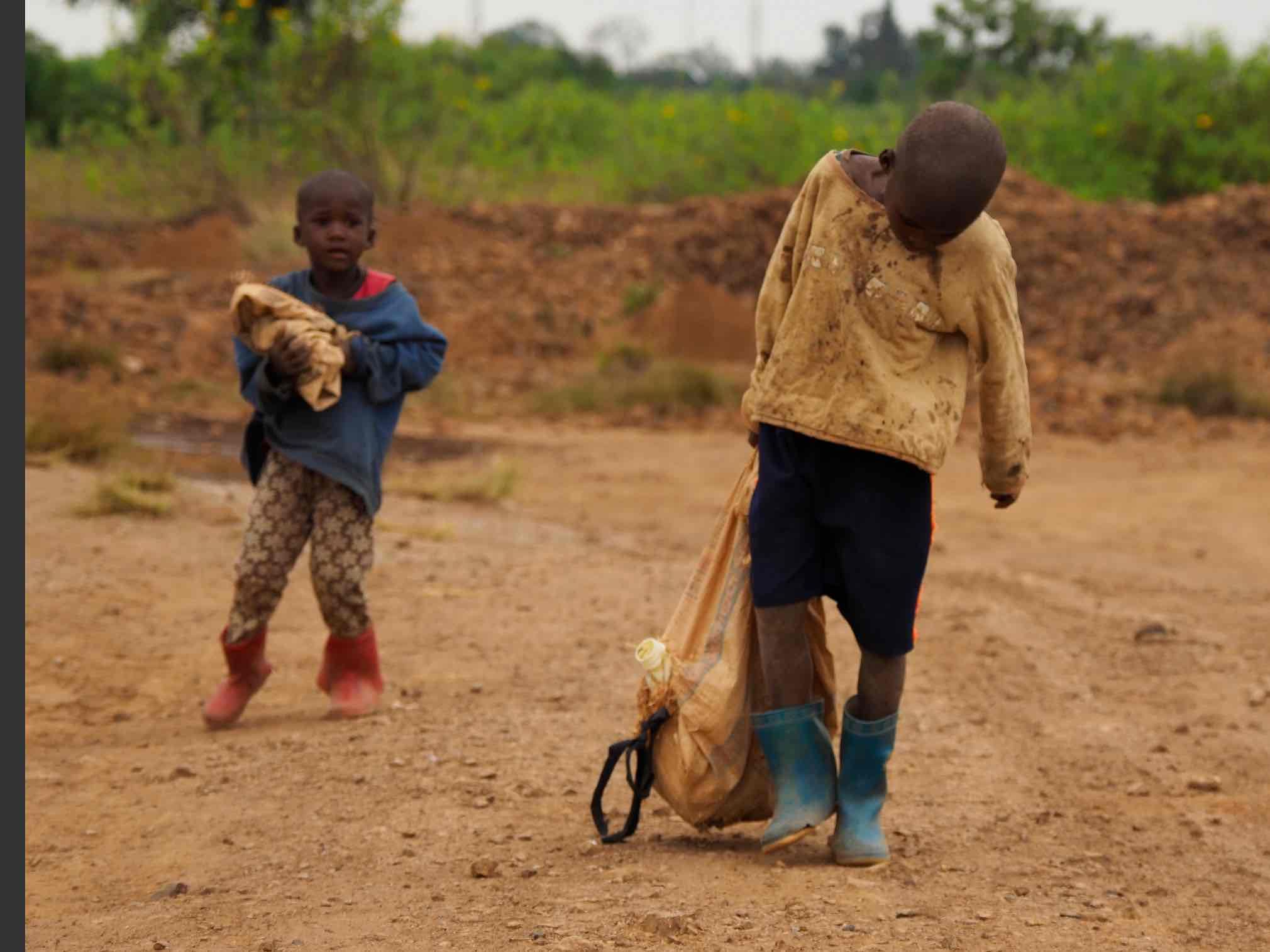 Abraham, 6, and Acili, 4, help their mother Debola Kunda to crush and carry stones. The levels of toxic lead are extreme but she said: ‘We know about that but what can we do when there are no others at home to take care of the children? How will we eat if we stay at home.’ Image by Larry C. Price. Zambia, 2017.