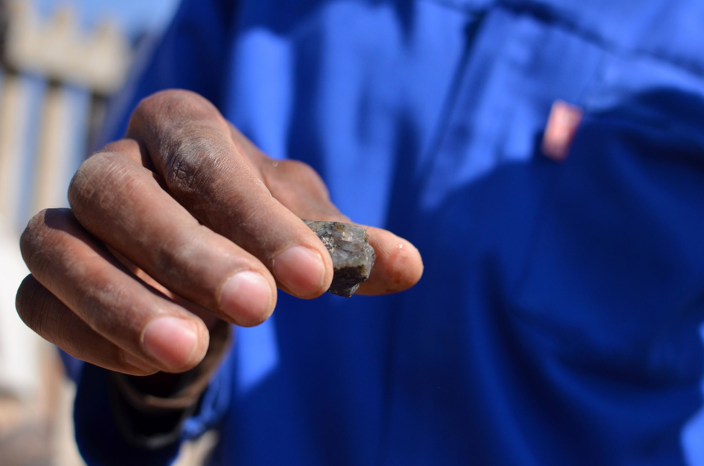 A South African, small-scale miner displays gold ore his operation dug out of a mine at the heritage park marking the discovery of gold on the Witwatersrand Basin. Image by Mark Olalde. South Africa, 2017.