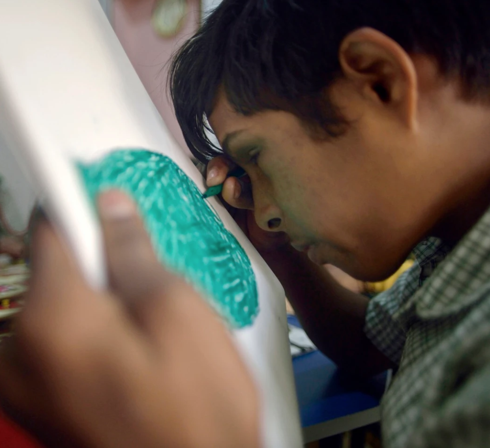 Akash, 16, who is sightless in one eye and partially sighted in other, does colouring at a special school of Chingrari Trust. Image by Rohit Jain. India, 2019. 