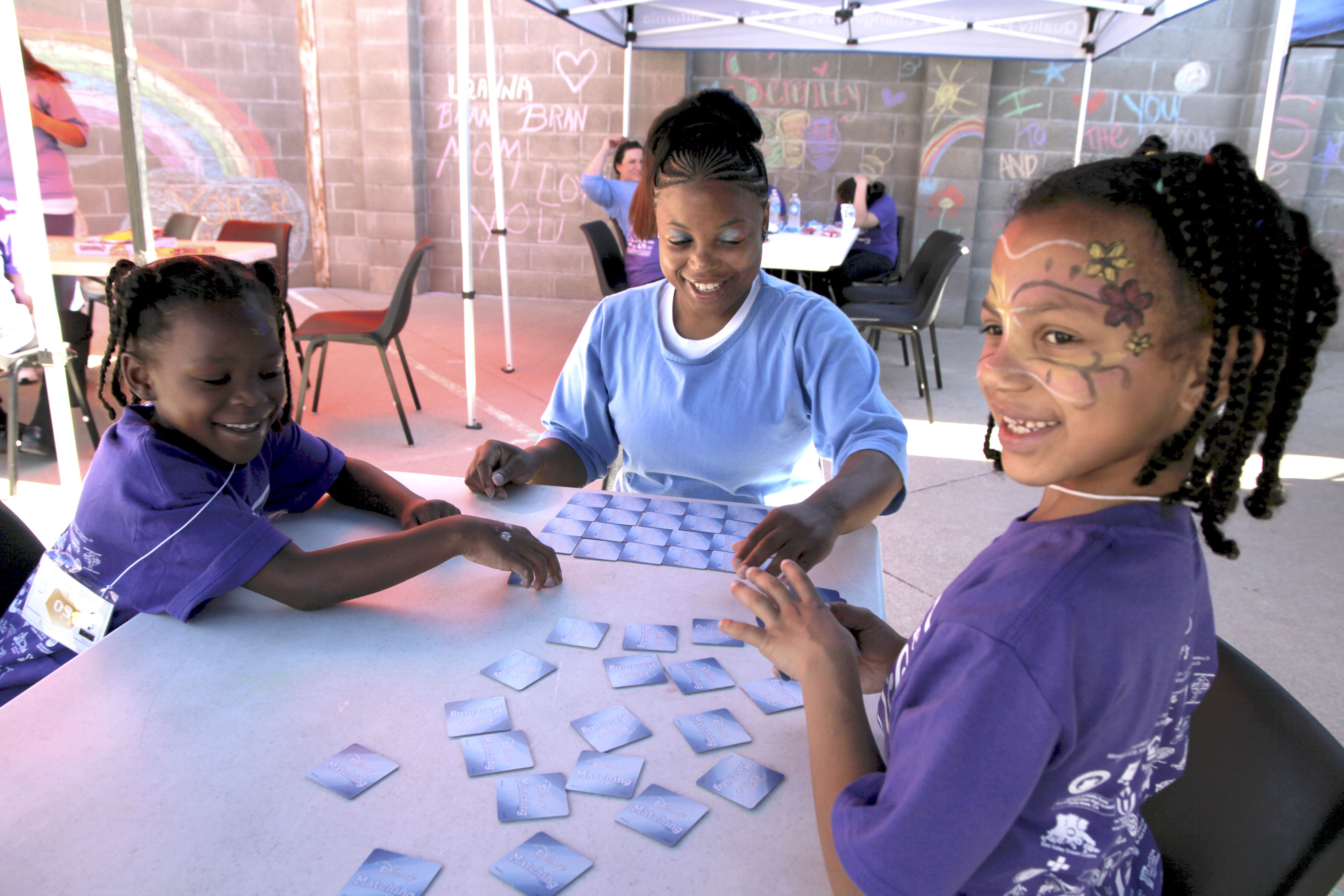 ALL SMILES Mi'Angel (left) and Mayal enjoy a card game with their mom, Donisha. Image by Jaime Joyce. United States, 2018.