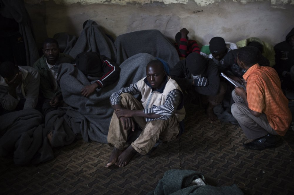FILE - In this Nov. 29, 2013, file photo, African migrants cover themselves with blankets after being captured by the Libyan Coast Guard while on a boat heading to Italy, in a detention center for illegal migrants in Abu Salim district on the outskirts of Tripoli, Libya. The United Nations opened its "Gathering and Departure Facility" in Libya a year ago as an alternative to imprisonment in such places as Abu Salim. But Libyan security officials and U.N. and other aid workers inside Libya confirmed that what was supposed to be a place of calm and order has fallen into chaos. Image by AP Photo/Manu Brabo. Libya, 2013.