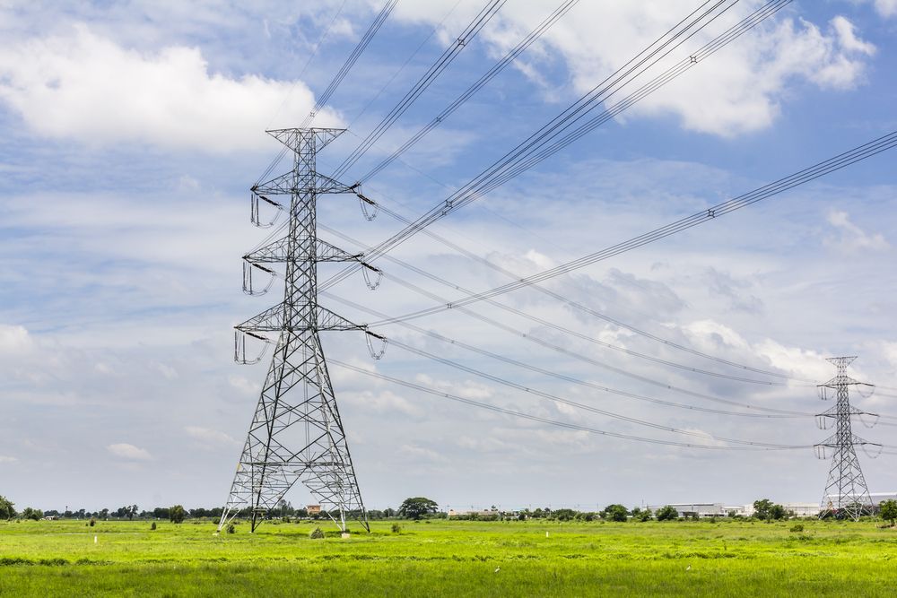 Hi-voltage electrical pylons against blue sky. Image by Happypix / Shutterstock.
