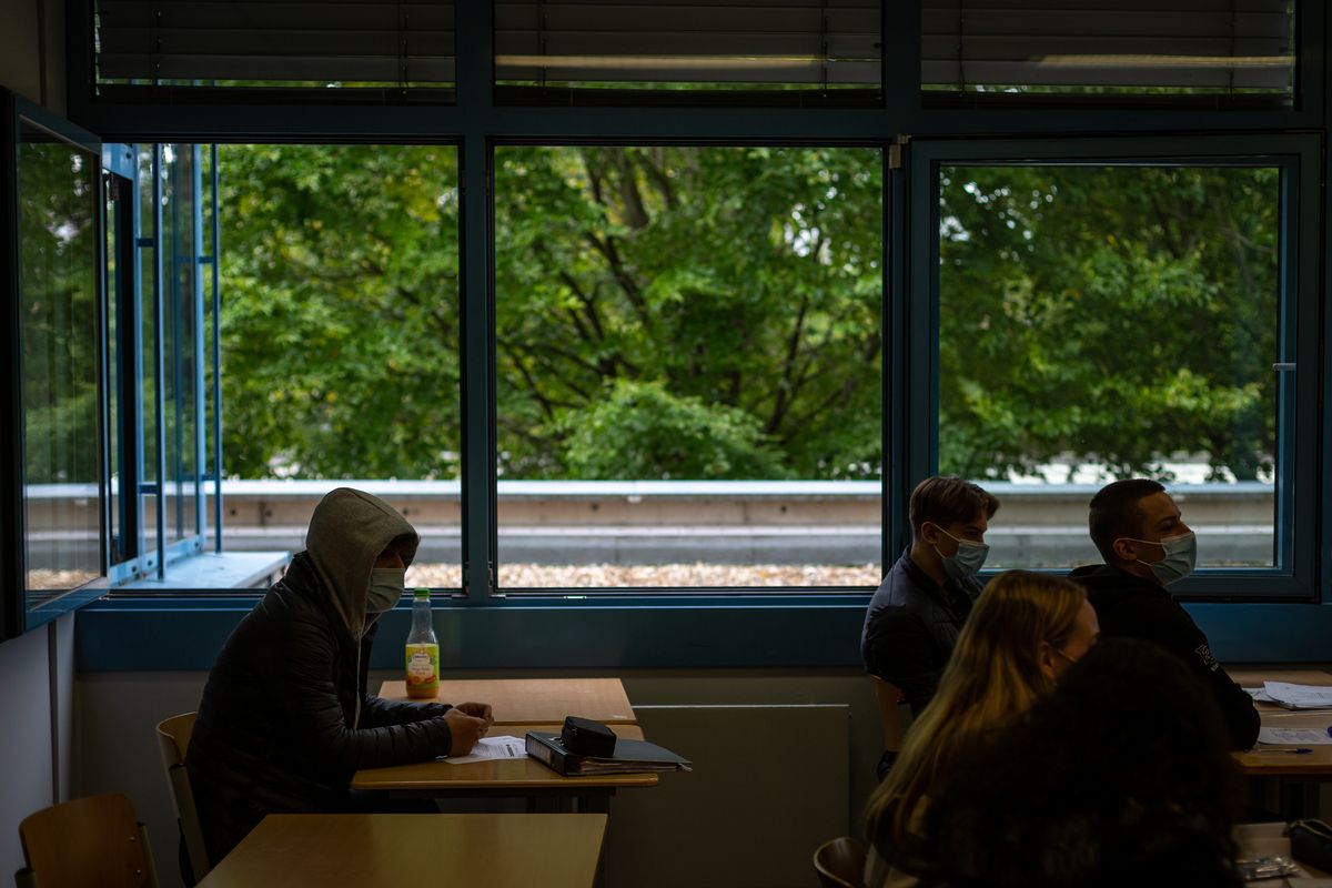 Students sit in a classroom with masks on and the windows wide up at a high school in Brühl, Germany, near Cologne. Image by Ryan Delaney. Germany, 2020.