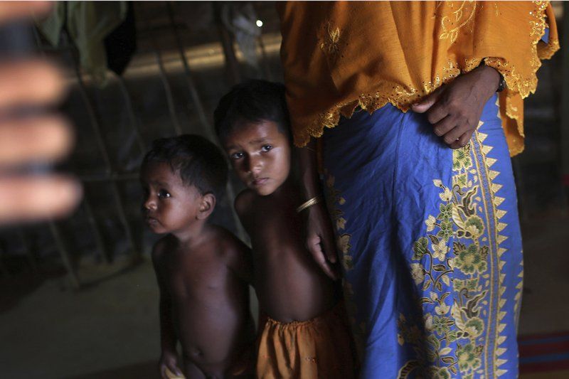 In this Sunday, Nov. 19, 2017, photo, K, 25, right, speaks to The Associated Press while her children watch cautiously beside her in their tent in Kutupalong refugee camp in Bangladesh. The Associated Press has found that the rape of Rohingya women by Myanmar’s security forces has been sweeping and methodical. The AP interviewed 29 women and girls who say they were raped by Myanmar’s armed forces, and found distinct patterns in their accounts, their assailants’ uniforms and the details of the rapes themselves. The most common attack involved groups of soldiers storming into a house, beating any children inside and then beating and gang raping the women. Image by Wong Maye-E. Bangladesh, 2017.