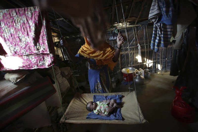 In this Sunday, Nov. 19, 2017, photo, K, 25, swings her two month old baby in her tent in Kutupalong refugee camp in Bangladesh. The Associated Press has found that the rape of Rohingya women by Myanmar’s security forces has been sweeping and methodical. The AP interviewed 29 women and girls who say they were raped by Myanmar’s armed forces, and found distinct patterns in their accounts, their assailants’ uniforms and the details of the rapes themselves. The most common attack involved groups of soldiers storming into a house, beating any children inside and then beating and gang raping the women. Image by Wong Maye-E. Bangladesh, 2017.
