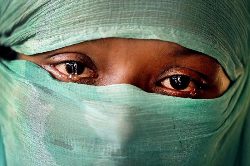 In this Wednesday, Nov. 22, 2017, photo, F, 22, who says she was raped by members of Myanmar’s armed forces in June and again in September, cries as she speaks to The Associated Press in her tent in Kutupalong refugee camp in Bangladesh. The Associated Press has found that the rape of Rohingya women by Myanmar’s security forces has been sweeping and methodical. The AP interviewed 29 women and girls who say they were raped by Myanmar’s armed forces, and found distinct patterns in their accounts, their assailants’ uniforms and the details of the rapes themselves. The most common attack involved groups of soldiers storming into a house, beating any children inside and then beating and gang raping the women. Image by Wong Maye-E. Bangladesh, 2017.