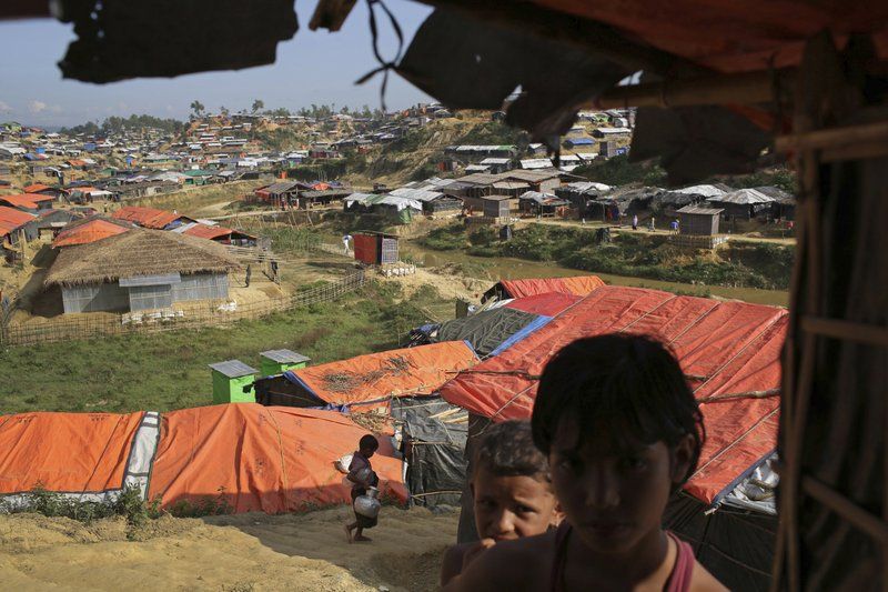 In this Sunday, Nov. 19, 2017, photo, Rohingya children stand in the shade of a tent in Kutupalong refugee camp in Bangladesh. The Associated Press has found that the rape of Rohingya women by Myanmar’s security forces has been sweeping and methodical. The AP interviewed 29 women and girls who say they were raped by Myanmar’s armed forces, and found distinct patterns in their accounts, their assailants’ uniforms and the details of the rapes themselves. The most common attack involved groups of soldiers storming into a house, beating any children inside and then beating and gang raping the women. Image by Wong Maye-E. Bangladesh, 2017.