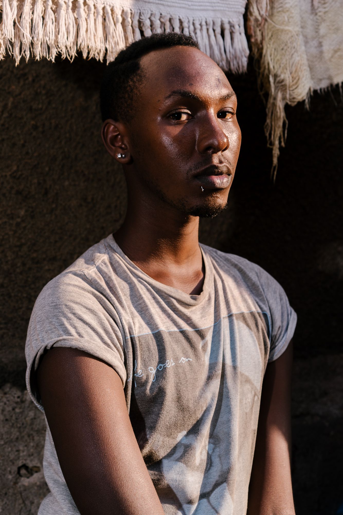 Javan, 19, a transgender woman, poses for a portrait near her mother's apartment in Kampala. She spent around eight months in Kenya as a refugee there after a mob beat her, stripped her naked and paraded her up and down the street yelling, "He's a homo," behind her near her Kampala home. Last summer, however, she returned to Uganda in order to make a stand. Image by Jake Naughton. Uganda, 2017.
