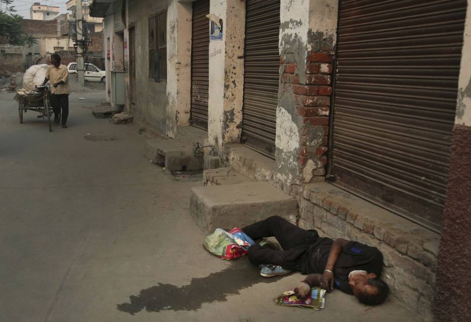 In this Oct. 31, 2019, photo, an Indian drug user lies unconscious by the side of a road in Kapurthala, in the northern Indian state of Punjab. Mass abuse of the opioid tramadol spans continents, from India to Africa to the Middle East, creating international havoc some experts blame on a loophole in narcotics regulation and a miscalculation of the drug’s danger. Punjab, the center of India's opioid epidemic, was among the latest to crack down on the tramadol trade. Researchers estimate about 4 million Indians use heroin or other opioids, and a quarter of them live in the Punjab, India's agricultural heartland bordering Pakistan. Image by Channi Anand / AP Photo. India, 2019.
