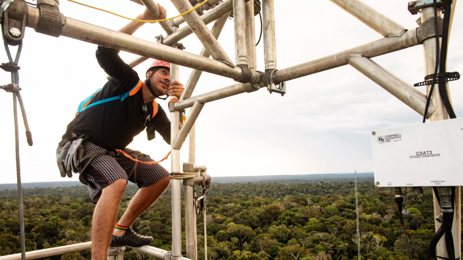 Researcher Delano Campos scales an 80-meter tower at the Amazon Tall Tower Observatory to collect air samples and maintain instruments. Image by Victor Moriyama. Brazil, 2019.