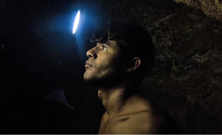 Franco León, a young miner who suffers from malaria, inspects an underground shaft near El Callao. Image by Bram Ebus. Venezuela, 2017.