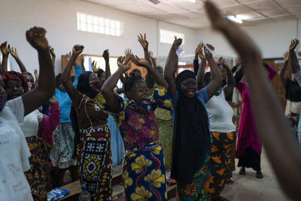 Pregnant women sing and dance before being assisted in a health unit where several women look for assistance with prenatal care in Koidu, district of Kono, Sierra Leone, Tuesday, Nov. 24, 2020. Image by Leo Correa/AP Photo. Sierra Leone, 2020.