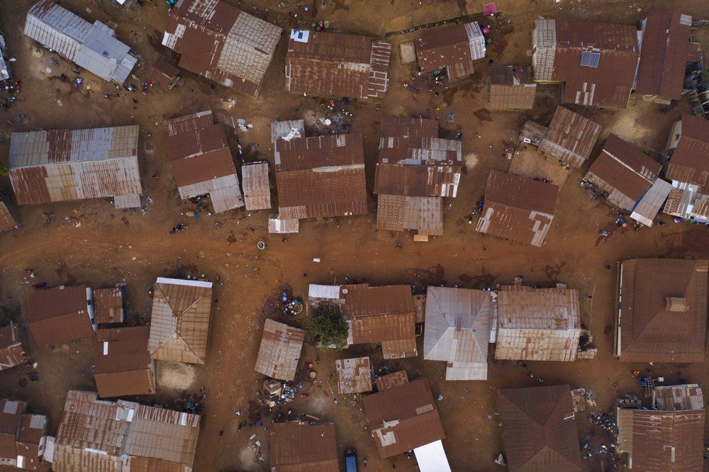 This Sunday, Nov. 22, 2020 photo shows homes in Komao village, on the outskirts of Koidu, district of Kono, Sierra Leone. Sierra Leone closed its borders before the country had its first COVID-19 case. As a result, the country has seen only 2,434 confirmed cases and 74 deaths. Only 76 of those cases were confirmed in Kono district, but the economic toll here has brought many families already living on the edge to a breaking point. Image by Leo Correa/AP Photo. Sierra Leone, 2020.