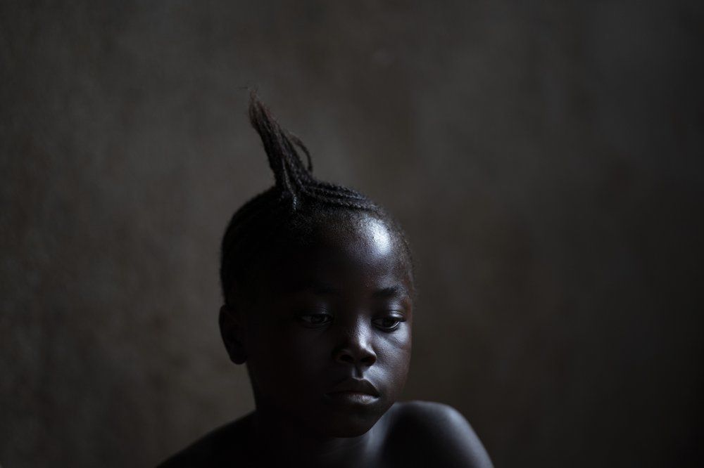 A girl watches a video clip on a portable DVD player in Komao village, outskirts of Koidu, district of Kono, Sierra Leone, Sunday, Nov. 22, 2020. Image by Leo Correa/AP Photo. Sierra Leone, 2020.
