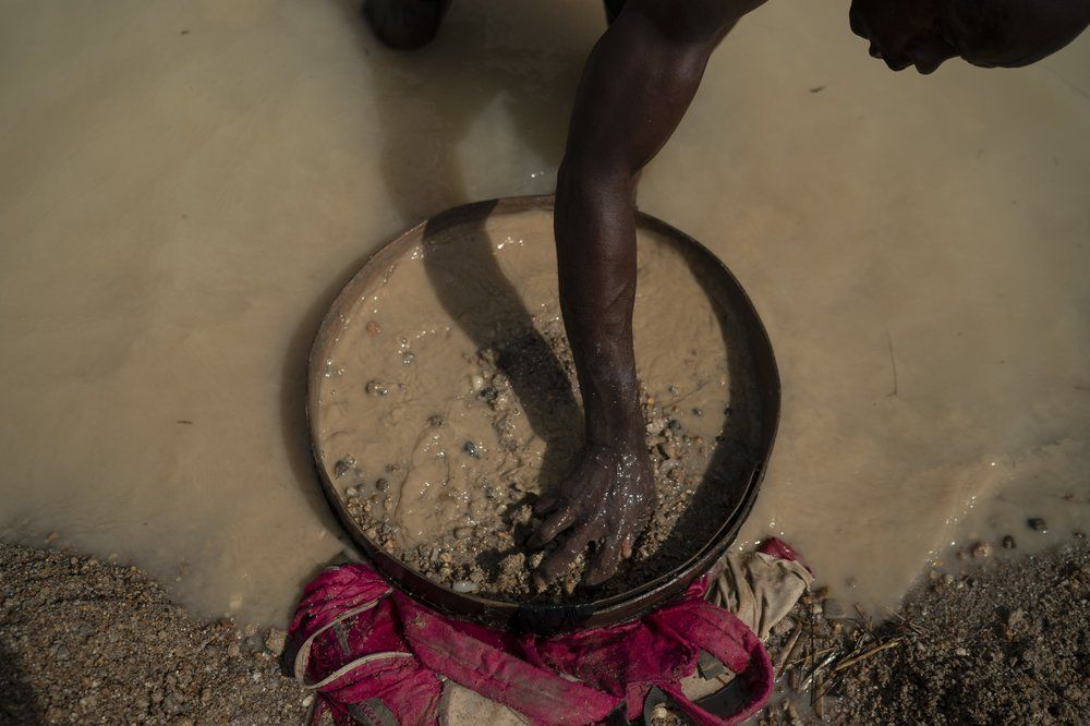 Aiah Kemoh uses a sieve as he looks for diamonds in a mining site in Koidu, district of Kono, Sierra Leone, Sunday, Nov. 22, 2020. The 43-year-old miner went back to mining just after the coronavirus restriction measures were lifted. "It's been difficult", says Kemoh, who built his family house with the money he earned from the diamonds. Image by Leo Correa/AP Photo. Sierra Leone, 2020.
