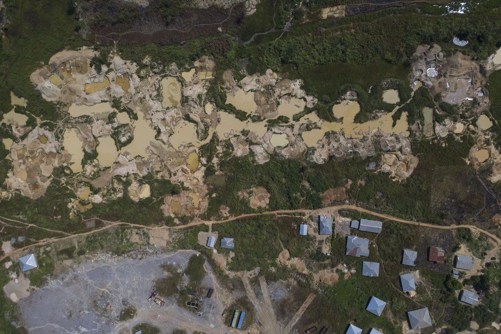 Houses stand next to a diamond mining site in Koidu, district of Kono, Sierra Leone, Sunday, Nov. 22, 2020. Mining operations have slowed with the global economy. Image by Leo Correa/AP Photo. Sierra Leone, 2020.
