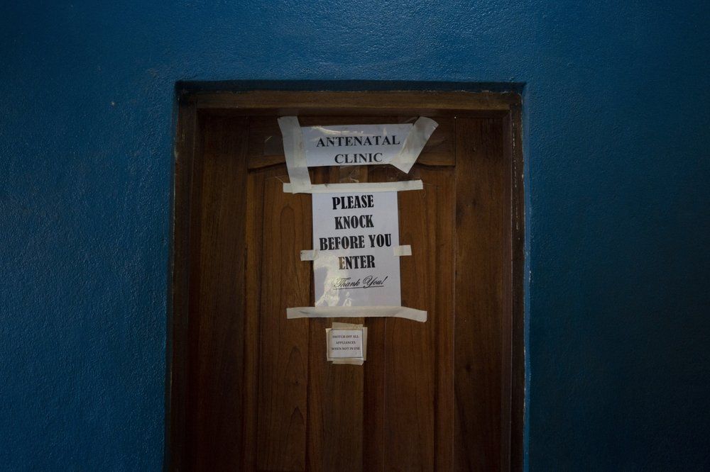 A sign taped on a door indicates an antenatal clinic office in a health unit where several women look for assistance for their prenatal care in Koidu, district of Kono, Sierra Leone, Tuesday, Nov. 24, 2020. In Sierra Leone, the rate of marriage under 18 had dropped from 56% in 2006 to 39% in 2017 _ a major achievement in the eyes of child protection activists. Then COVID-19 hit, schools closed in March and child marriages accelerated as many village girls who had been attending classes in nearby towns returned home to their parents. Image by Leo Correa/AP Photo. Sierra Leone, 2020.
