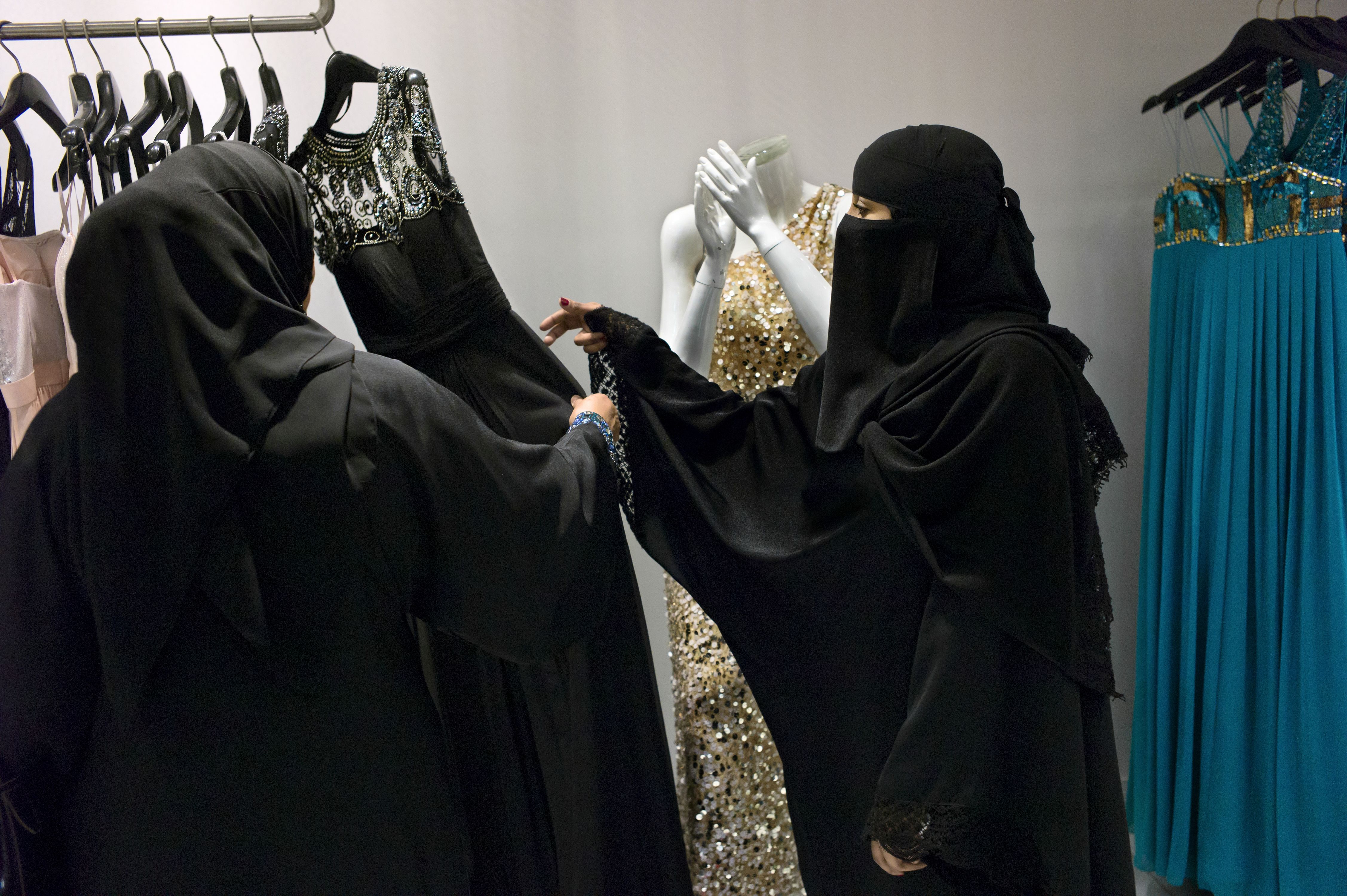 A Saudi employee helps a customer at a dress shop in Al Faisaliah Mall. Image by Kate Brooks. Saudi Arabia, 2013.