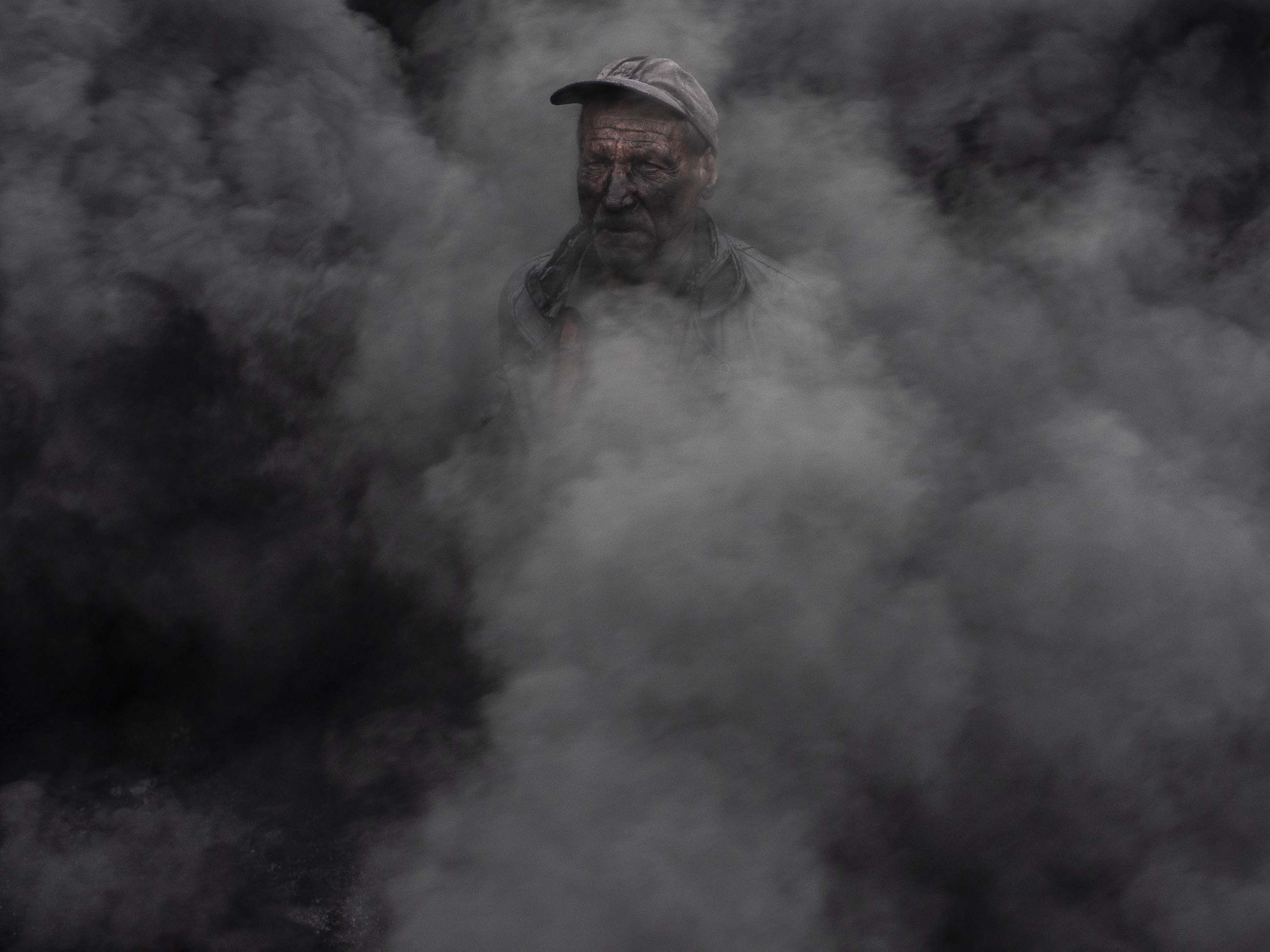 A worker at an outdoor quicklime kiln in the southeastern village of Kosturino, Macedonia. The operation — just one of dozens of prominent sources of air pollution in the country — burns tires for fuel. Image by Larry C. Price. Macedonia, 2018.