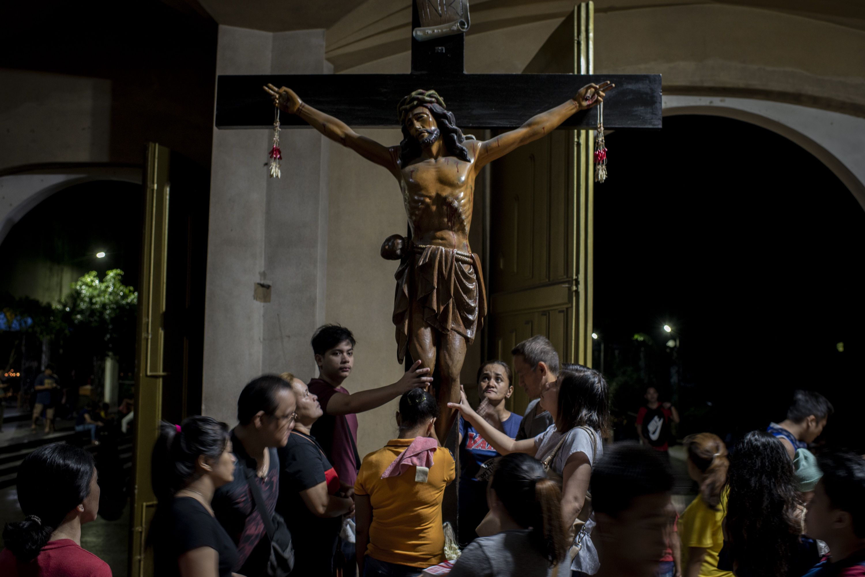 Parishioners touch the crucifix after an evening service at Baclaran Church in Manila. Image by Eloisa Lopez. Philippines, 2018.