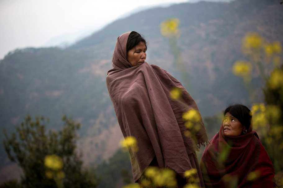 Sauri (left) and her sister-in-law Birma stand in the spot where Sauri's 17-year-old daughter, Laxmi, recently burned to death while sleeping in a chaupadi shed in an area far from the family's home, near Dhakari village, Achham, Nepal. "I have many daughters," said Sauri, "but she was the one who was always with me." The family has since destroyed the shed. Image by Allison Shelley. Nepal, 2012.