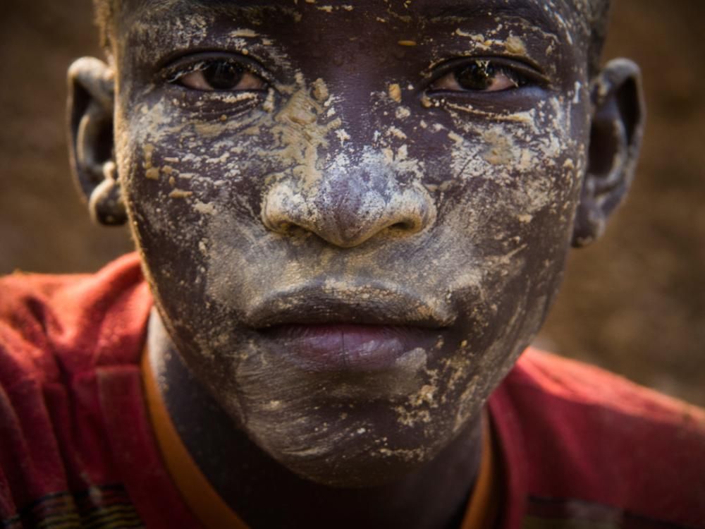 A young boy near the end of his shift at the Fandjora gold mine. After the famines in Burkina Faso forced families off their farms  in the 1980s, artisanal or small-scale mining took root. It has now become the nation's third largest export. Although child labor is illegal in the country, leaders and entrepreneurs, eager to tap the vast reserves, often look the other way while young mine workers risk long-term health problems caused by exposure to dust, toxic chemicals, and heavy metals.  Image by Larry C. Price. Burkina Faso, 2013.