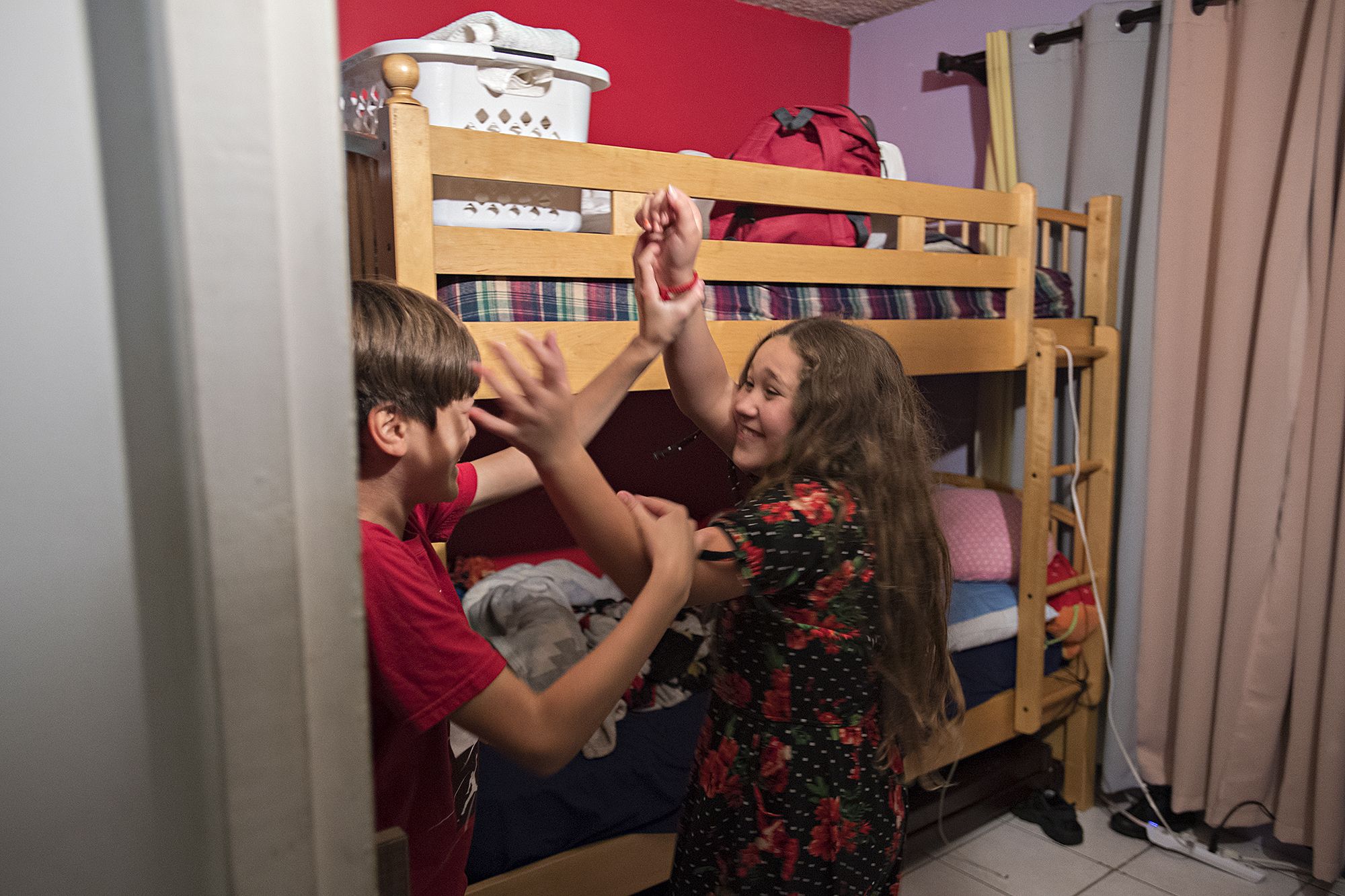Edward Flores, left, and his sister, Rayma, playfully wrestle in the children’s bedroom as they get restless waiting for Thanksgiving dinner. The combination of rainy weather and their parents’ neighborhood safety concerns had kept them cooped up in the small, two-bedroom apartment in Tijuana, Mexico, for the majority of the day. Image by Amanda Cowan. Mexico, 2019.