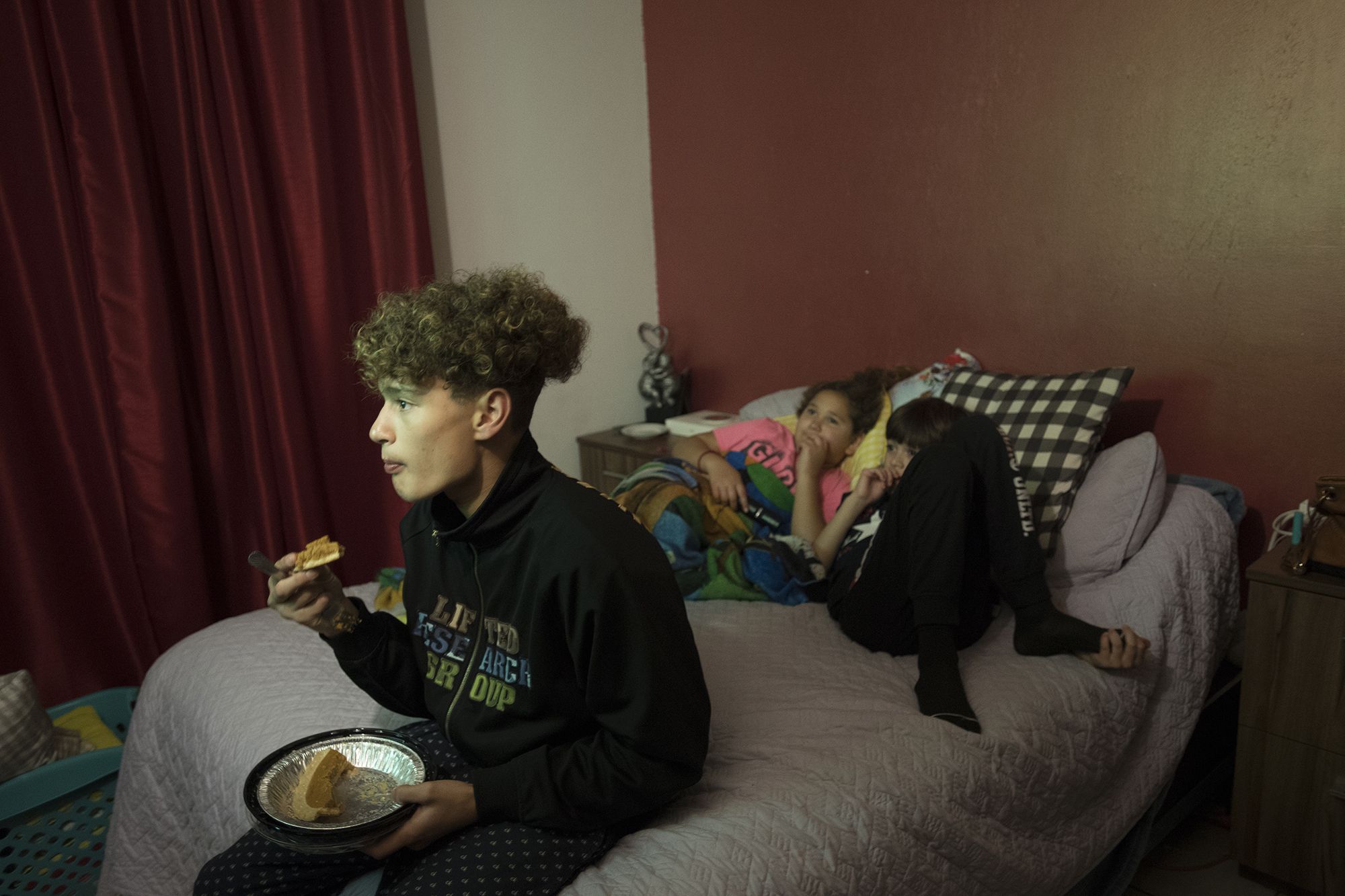 Raymond Flores polishes off the remainder of the pumpkin pie while watching Netflix before Thanksgiving dinner with his sister, Rayma, and brother, Edward. Image by Amanda Cowan. Mexico, 2019.