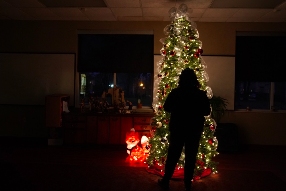 A Memphis victim of domestic violence stands in the glow of a Christmas tree in a Mid-South shelter. She escaped her abuser but is isolated from family over the holidays. Severe cases of domestic violence are on the rise during the pandemic. Image by Karen Pulfer Focht/Special to Daily Memphian. United States, 2020.