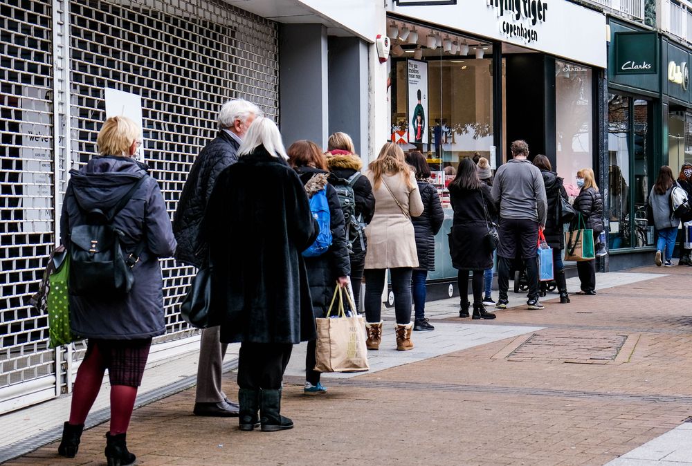 A line of people queuing to enter a shop on December 9 during COVID-19 Tier 2 restrictions in Kingston, London. Image by Richard M Lee / Shutterstock. United Kingdom, 2020.