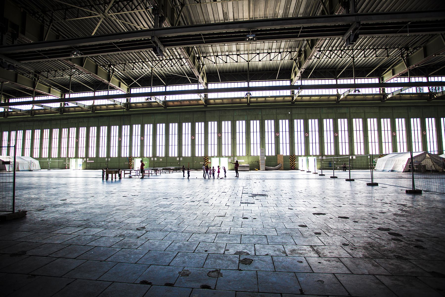 Children play in a hanger in Tempelhof airport, once a Nazi hanger and now home to over 2000 refugees. Image by Emily Kassie. Germany, 2016.