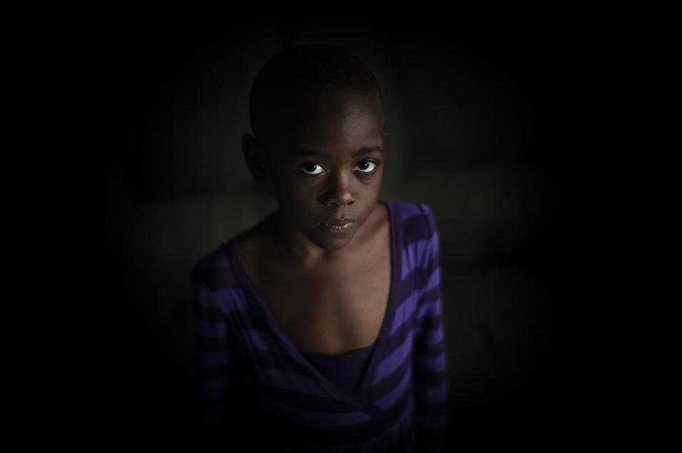 In this photo taken Wednesday, Nov. 6, 2019, Ange Mucyo Izere, 6, who has bone marrow cancer and takes oral liquid morphine for her pain, stands inside her home in the Gitega neighborhood of the capital Kigali, Rwanda. While people in rich countries are dying from overuse of prescription painkillers, people in Rwanda and other poor countries are suffering from a lack of them, but Rwanda has come up with a solution to its pain crisis - it's morphine, which costs just pennies to produce and is delivered to households across the country by public health workers. Image by Ben Curtis / AP Photo. Rwanda, 2019.