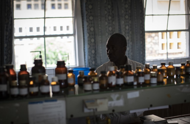 In this photo taken Thursday, Nov. 7, 2019, biochemist Denys Rukarata works in the room where he tests locally-produced oral liquid morphine for purity, as well as other medicines, at the Pharmaceutical Laboratory of Rwanda where the country's liquid morphine is made from powder, in Butare, Rwanda. While people in rich countries are dying from overuse of prescription painkillers, people in Rwanda and other poor countries are suffering from a lack of them, but Rwanda has come up with a solution to its pain crisis - it's morphine, which costs just pennies to produce and is delivered to households across the country by public health workers. Image by Ben Curtis / AP Photo. Rwanda, 2019.