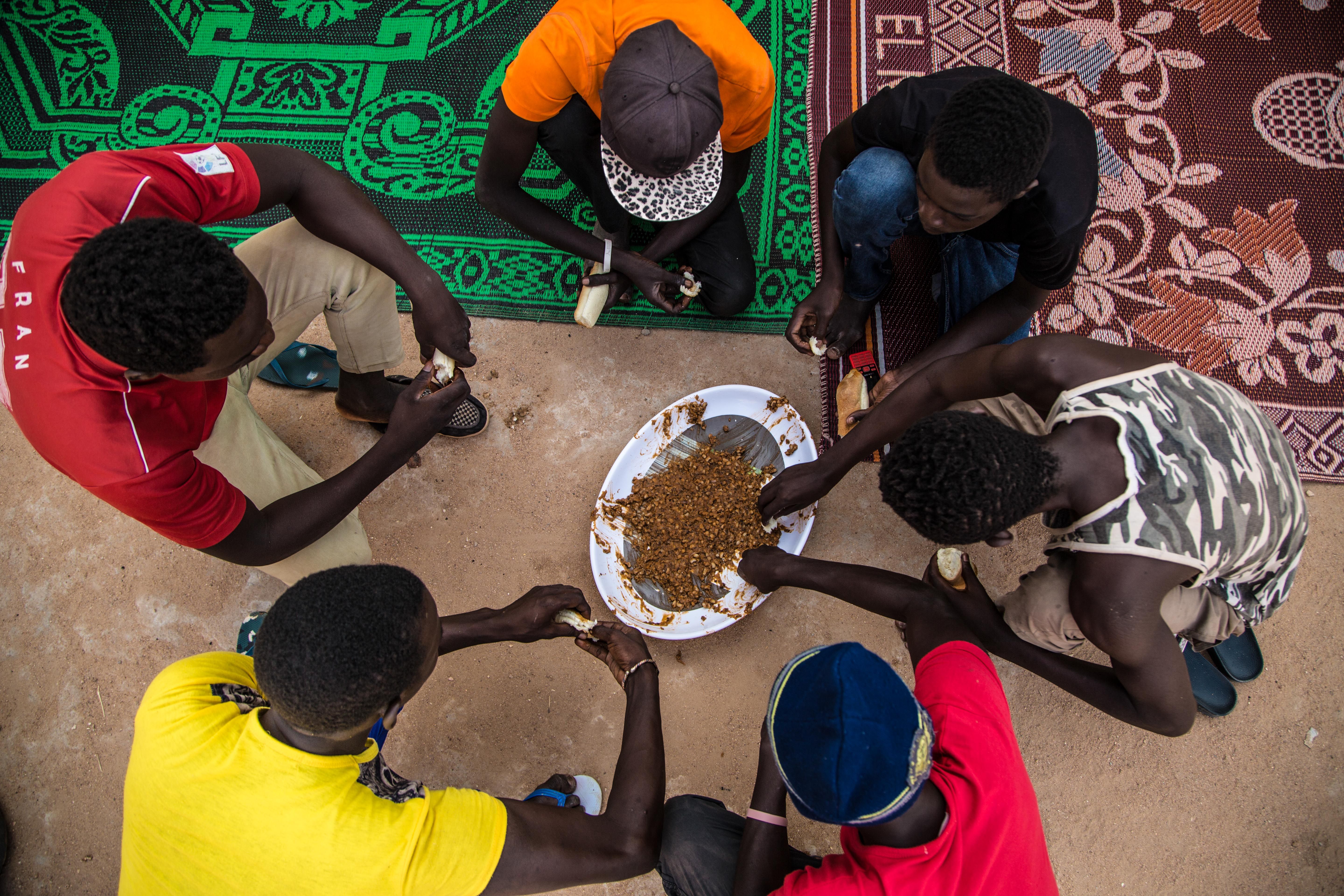 Migrants eat a meager meal of beans before making the dangerous trek into the Saharan desert and on to Libya. Image by Emily Kassie. Niger, 2016.