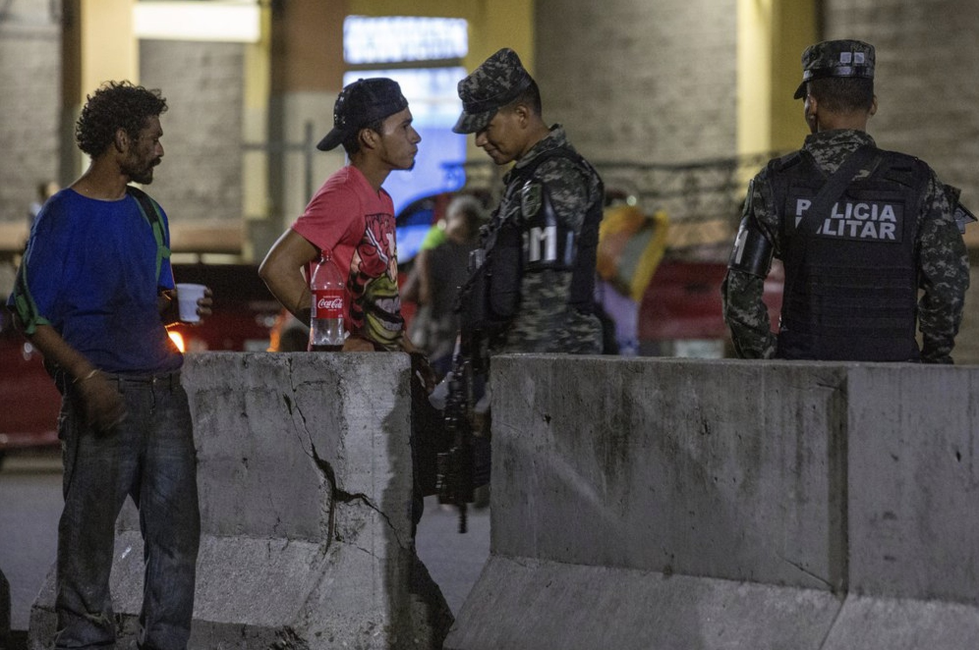 Military police patrol the main bus station in San Pedro Sula, Honduras, on Nov. 28, 2019. Until a few months ago, the bus station was crowded with migrants heading north towards the U.S. Now many buses leave with just a few passengers. Image by Moises Castillo/ AP Photo. Honduras, 2019.