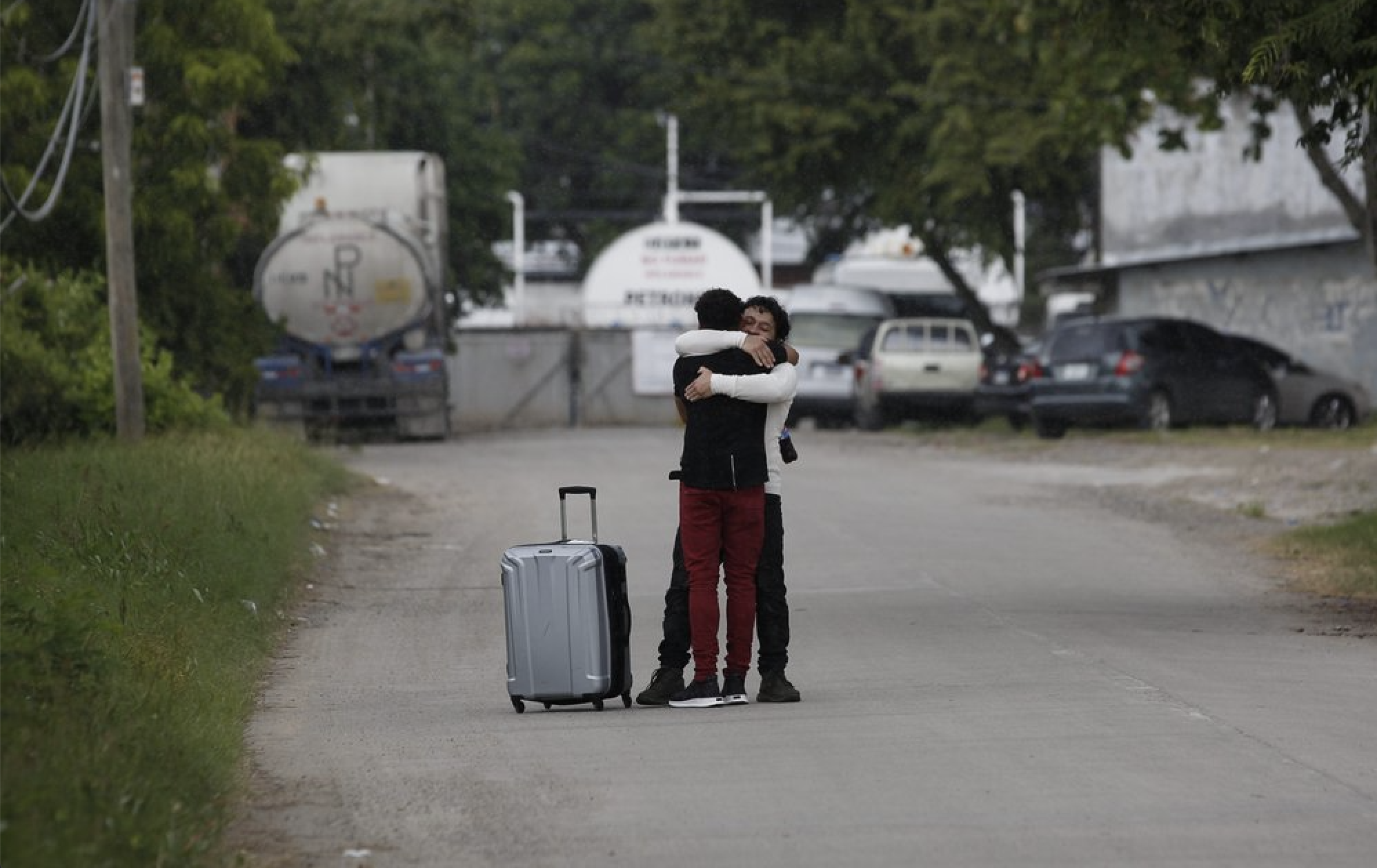 A man who was deported from the United States, foreground, is welcomed by a relative outside the Ramon Villeda International Airport in La Lima, Honduras on Nov. 29, 2019. While immigration advocates acknowledge some cases don't meet the legal standard for asylum, they believe the real intention of the ever-tighter White House policies are to discourage migrants - even those with valid needs for asylum - from trying to reach the U.S. Image by Moises Castillo/ AP Photo. Honduras, 2019.