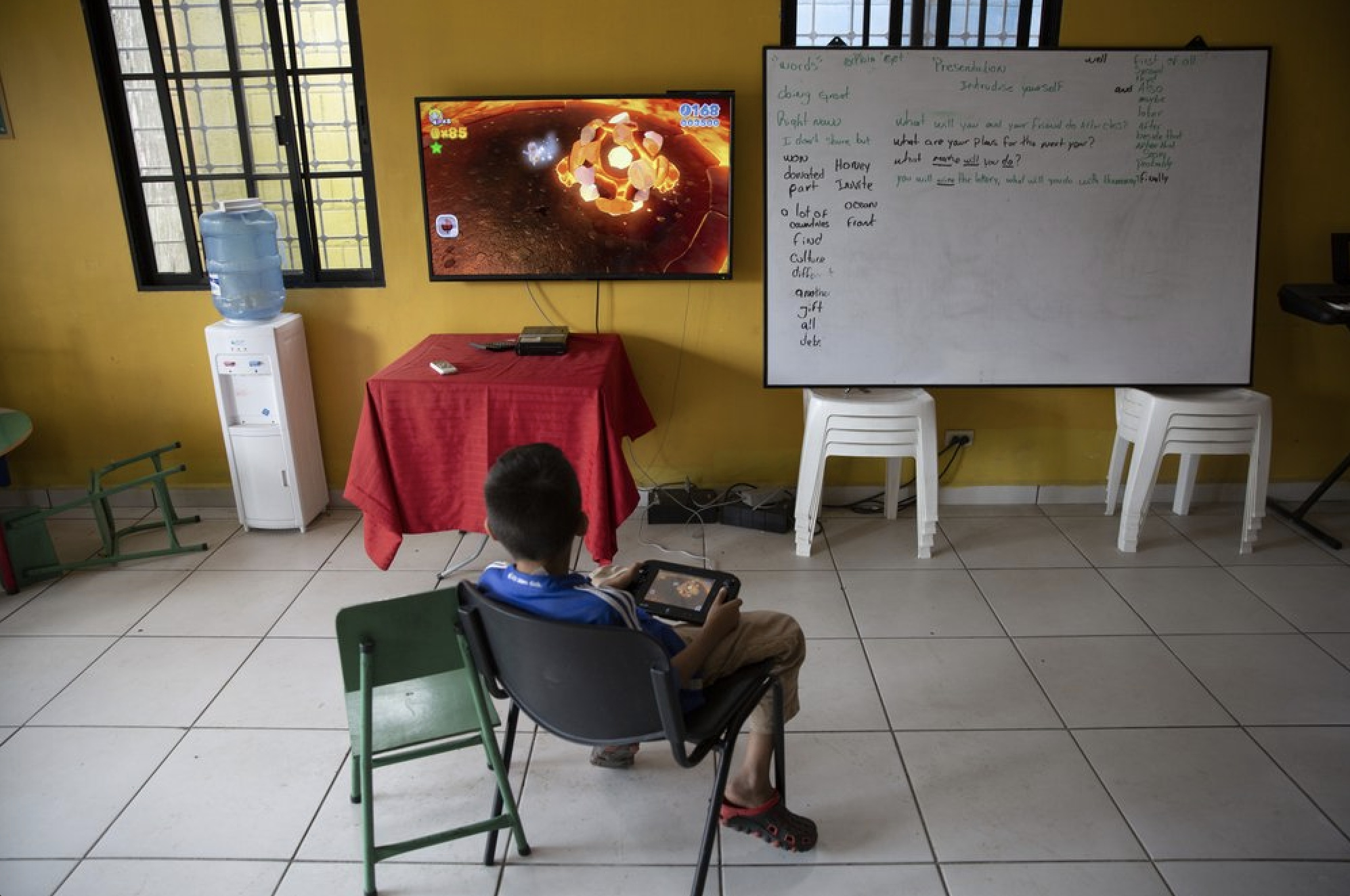 A boy plays video games inside a help center for young people living in dangerous zones, in the Rivera Hernandez neighborhood of San Pedro Sula, Honduras, on Dec. 2, 2019. Image by Moises Castillo/ AP Photo. Honduras, 2019.