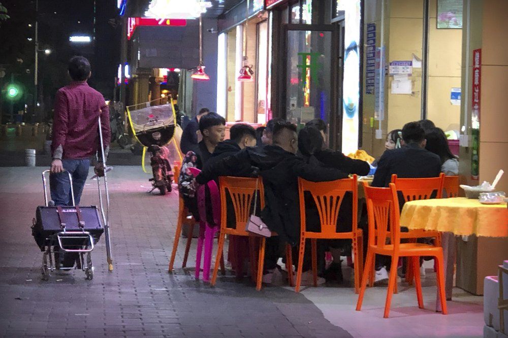 In this Dec. 6, 2019, photo, Wu Yi, who has struggled with Oxycontin abuse, wheels his portable amplifier past customers at an all-night restaurant in Shenzhen in southern China's Guangdong Province. Officially, pain pill abuse is an American problem, not a Chinese one. But people in China have fallen into opioid abuse the same way many Americans did, through a doctor's prescription. And despite China's strict regulations, online trafficking networks, which facilitated the spread of opioids in the U.S., also exist in China. Image by Mark Schiefelbein/ AP Photo. China, 2019.