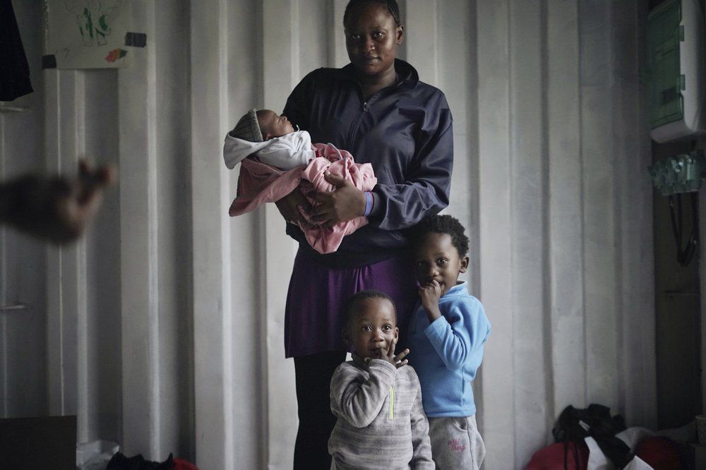 In this Sept. 23, 2019 photo, Prudence Aimee, 30, from Cameroon poses for a photo with her children, from left Ange, Wifrid, 1, and William, 3, aboard the humanitarian rescue ship Ocean Viking in Italian waters off the Sicilian town of Messina, southern Italy, hours before disembarking. Aimee left Cameroon in 2015, and when her family heard nothing from her for two years, they thought she was dead. But she was in detention and incommunicado. In nine months at Libya's Abu Salim detention center, she saw “European Union milk” and diapers delivered by UN staff pilfered before they could reach migrant children, including her toddler son. Aimee herself would spend two days at a time without food or drink. Image by Renata Brito/AP Photo. Italy, 2019.