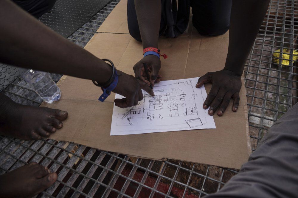 In this Sept. 23, 2019 photo, rescued migrants draw a map of the Zawiya, Libya detention center run by the al-Nasr Martyrs militia. Migrants at the center are tortured for ransoms to be freed and trafficked for more money, only to be intercepted at sea by the coast guard and brought back to the center, according to more than a dozen migrants, Libyan aid workers, Libyan officials and European human rights groups. Image by Renata Brito/AP Photo. Libya, 2019.