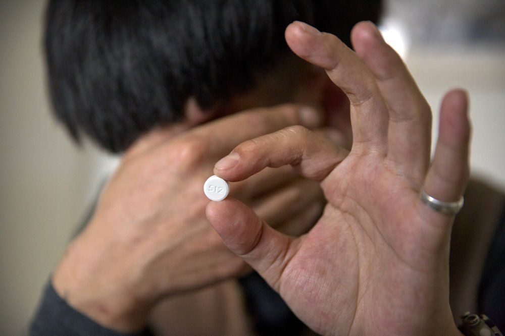 In this March 28, 2019, photo, Yin Hao, who also goes by Yin Qiang, holds a Tylox pill while sitting in a tea house in Xi'an, northwestern China's Shaanxi Province. Officially, pain pill abuse is an American problem, not a Chinese one. But people in China have fallen into opioid abuse the same way many Americans did, through a doctor's prescription. And despite China's strict regulations, online trafficking networks, which facilitated the spread of opioids in the U.S., also exist in China. Image by Mark Schiefelbein/ AP Photo. China, 2019.