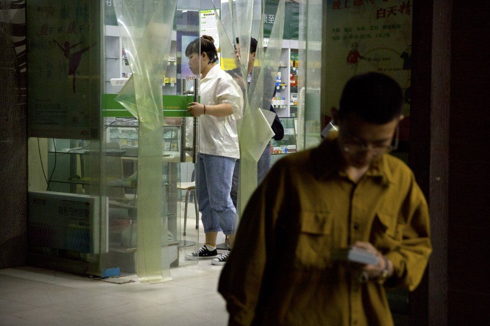 In this March 28, 2019, photo, people shop at a pharmacy that sold Tylox without a prescription in Xi'an in northwestern China's Shaanxi Province. Despite officially low numbers of prescription drug abuse, the Chinese government was worried enough about pain pill abuse that it pulled Tylox from most pharmacies in September. Officially, pain pill abuse is an American problem, not a Chinese one. But people in China have fallen into opioid addiction the same way many Americans did, through a doctor's prescription. And despite China's strict regulations, online trafficking networks, which facilitated the spread of opioids in the U.S., also exist in China. Image by Mark Schiefelbein/ AP Photo. China, 2019.