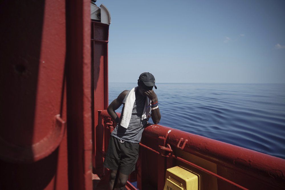 In this Sept. 14, 2019 photo, Amidou from Cameroon touches his face aboard the Ocean Viking humanitarian ship as it sails to Italy in Mediterranean Sea. He was rescued from an overcrowded rubber boat north of Libya as he tried to cross to Europe. While in Libya he spent five weeks in various parts of the Zawiya detention center where he says he was forced to unearth weapons in the desert. Image by Renata Brito/AP Photo. Italy, 2019.