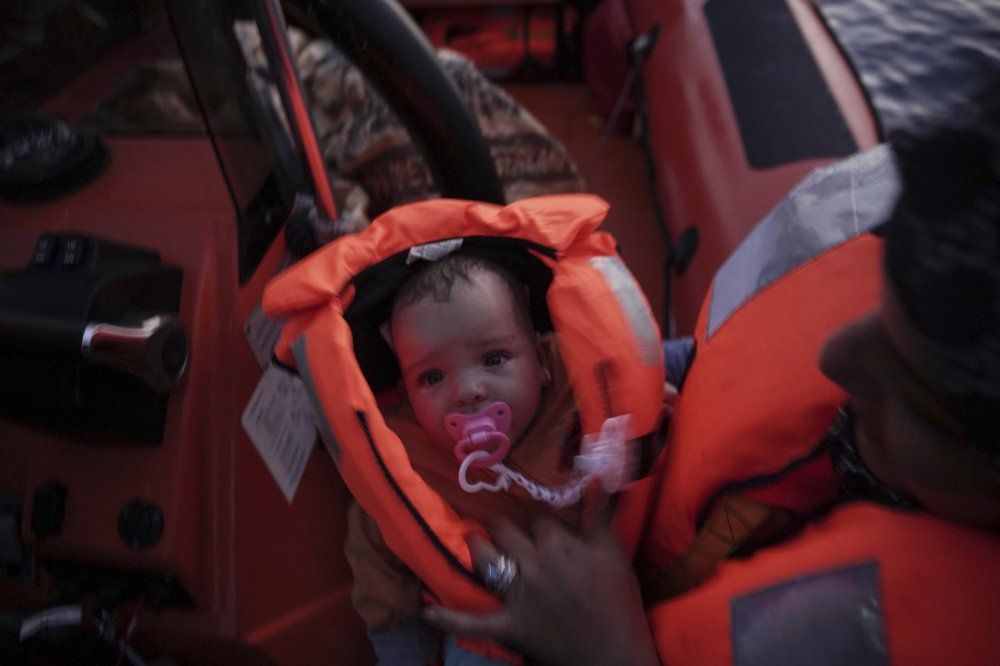 In this Sept. 19, 2019 photo, 4-month-old Mira is held by her mother during a rescue by the Ocean Viking humanitarian ship in the Mediterranean Sea. Her mother says their family escaped Libya after their home was destroyed in the war. Image by Renata Brito/AP Photo. Libya, 2019.