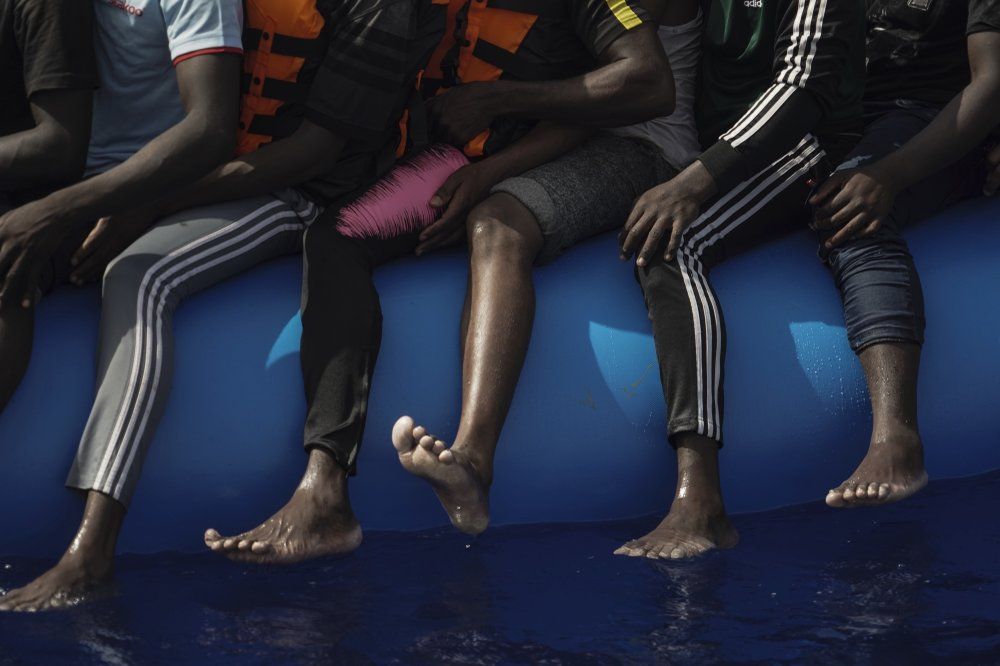 In this Sept. 17, 2019 photo, migrants sit on an overcrowded rubber boat as they wait to be rescued by the Ocean Viking humanitarian ship run by SOS Mediterranée and Doctors Without Borders in the Mediterranean Sea north of Libya. The EU has sent more than 327.9 million euros to Libya, with an additional 41 million approved in early December, largely funneled through UN agencies. However, the AP found that in a country without a functioning government, huge sums of European money have been diverted - in some cases with the knowledge of UN officials - to intertwined networks of militiamen, traffickers and coast guard members who exploit migrants. Image by Renata Brito/AP Photo. Libya, 2019.