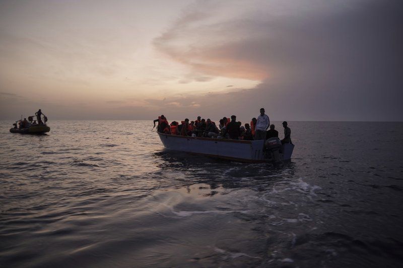 In this Sept. 19, 2019 photo, migrants on an overcrowded wooden boat wait to be rescued by the Ocean Viking humanitarian ship in the Mediterranean Sea. The misery of migrants in Libya has spawned a thriving and highly lucrative business, in part funded by the EU and enabled by the United Nations, an Associated Press investigation has found. Image by Renata Brito/AP Photo. Libya, 2019.