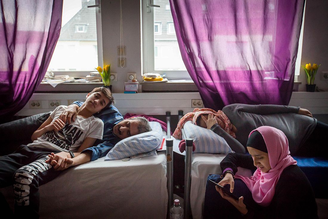From left, Milad rests in Germany with his father, Mohammed; his mother, Aziza; and his sister Mina. Milad’s sister Mahya is not pictured. The five of them fled Afghanistan last year. Image by Diana Markosian. Germany, 2017.