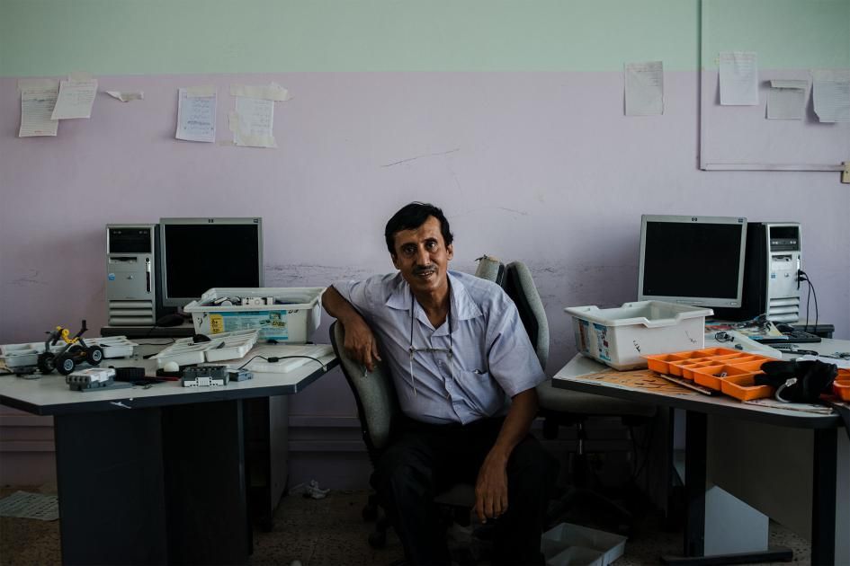 Fathi sits in the computer and robotics lab in the school where he teaches English. Image by Alex Potter. Yemen, 2018.
